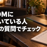 チェック欄が並んだメモ帳と鉛筆、ノートパソコンが置かれた夜のデスク